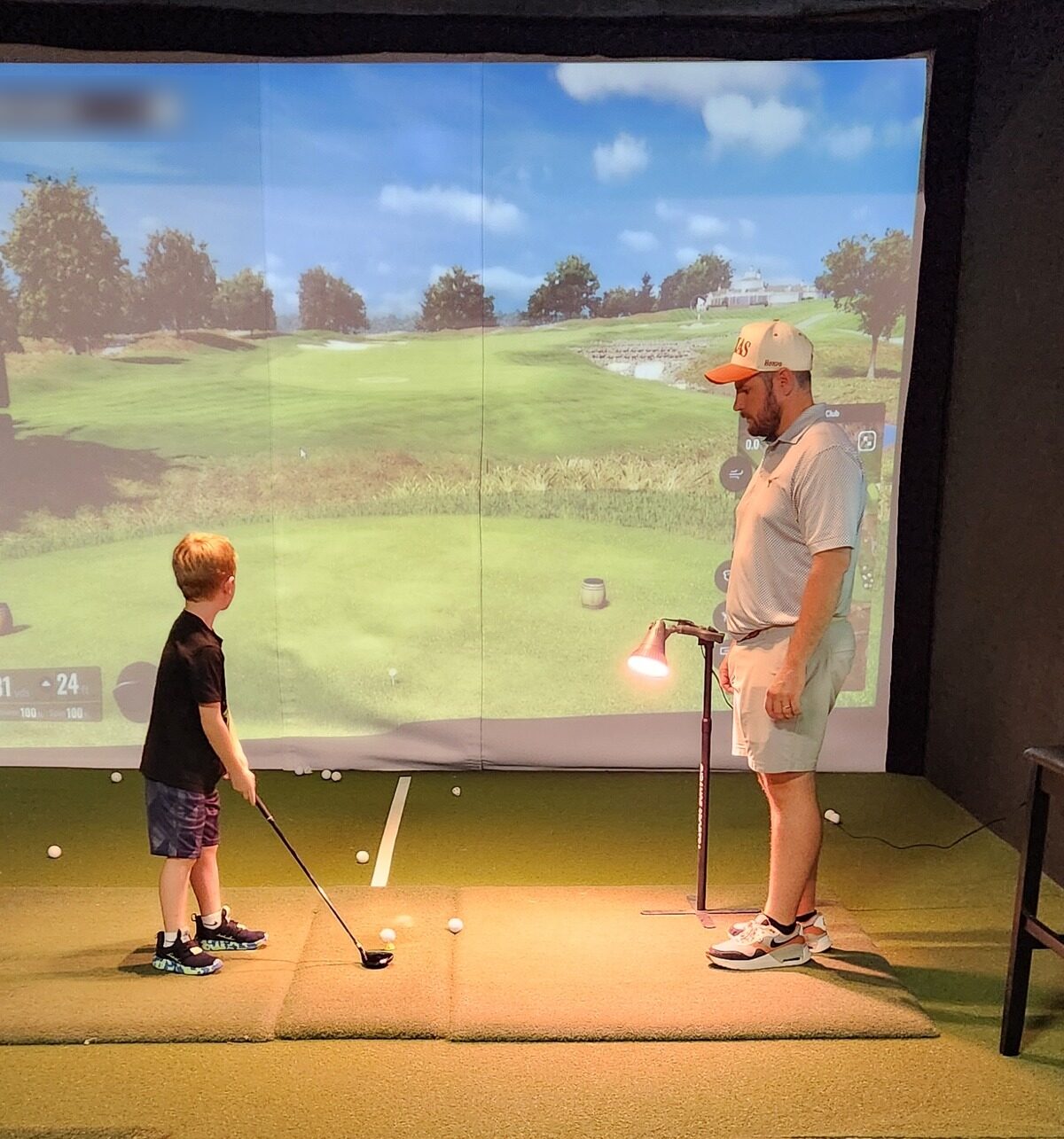 A father and son on screen together in a private TrackMan simulator bay at Match Play Golf